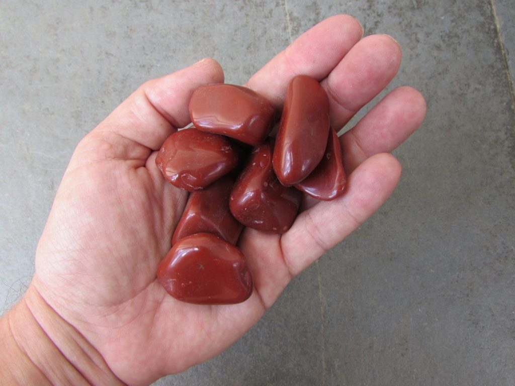 mão segurando várias pedras Jaspe Vermelho