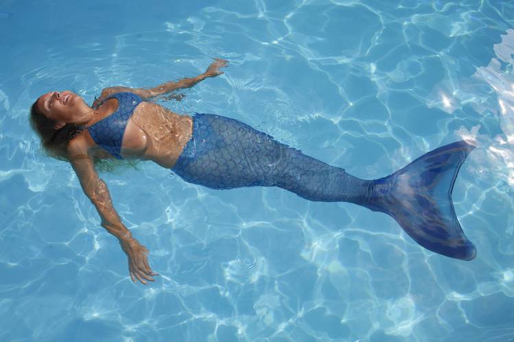 sereia com calda azul flutuando sobre a piscina