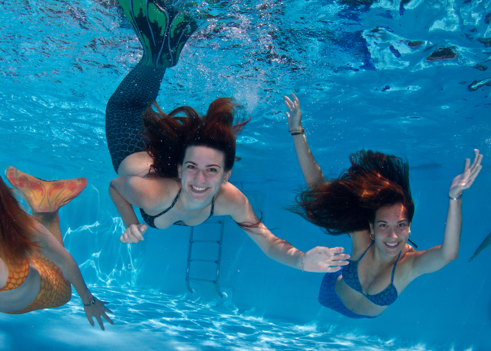 três sereias nadando livremente na piscina