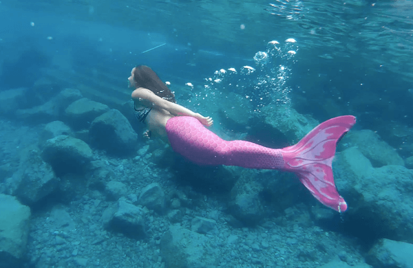 sereia nadando livremente no mar com uma calda rosa