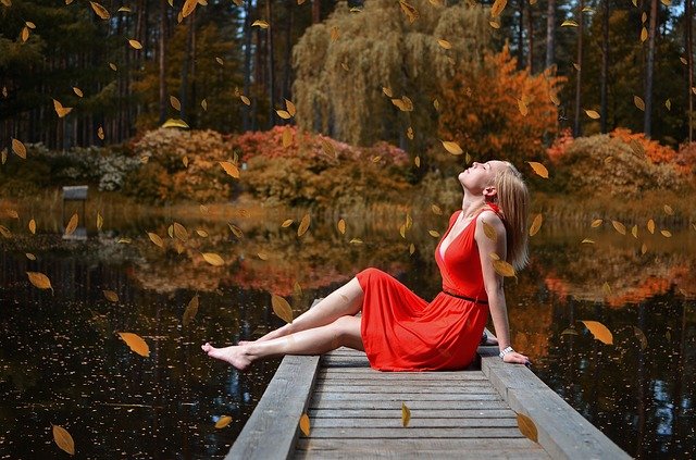 mulher de vestido vermelho sentada em uma ponte