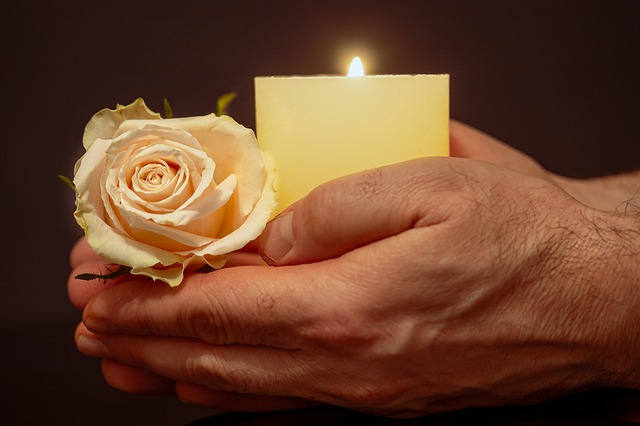 mão segurando uma vela e uma rosa