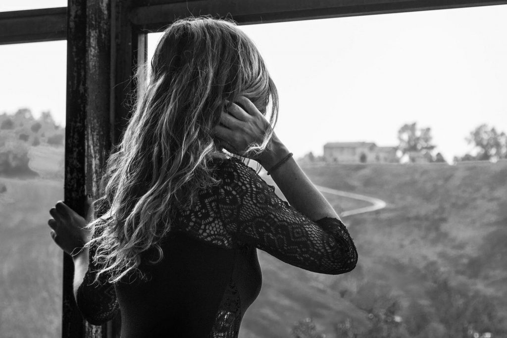 mulher abandonada olhando pela janela